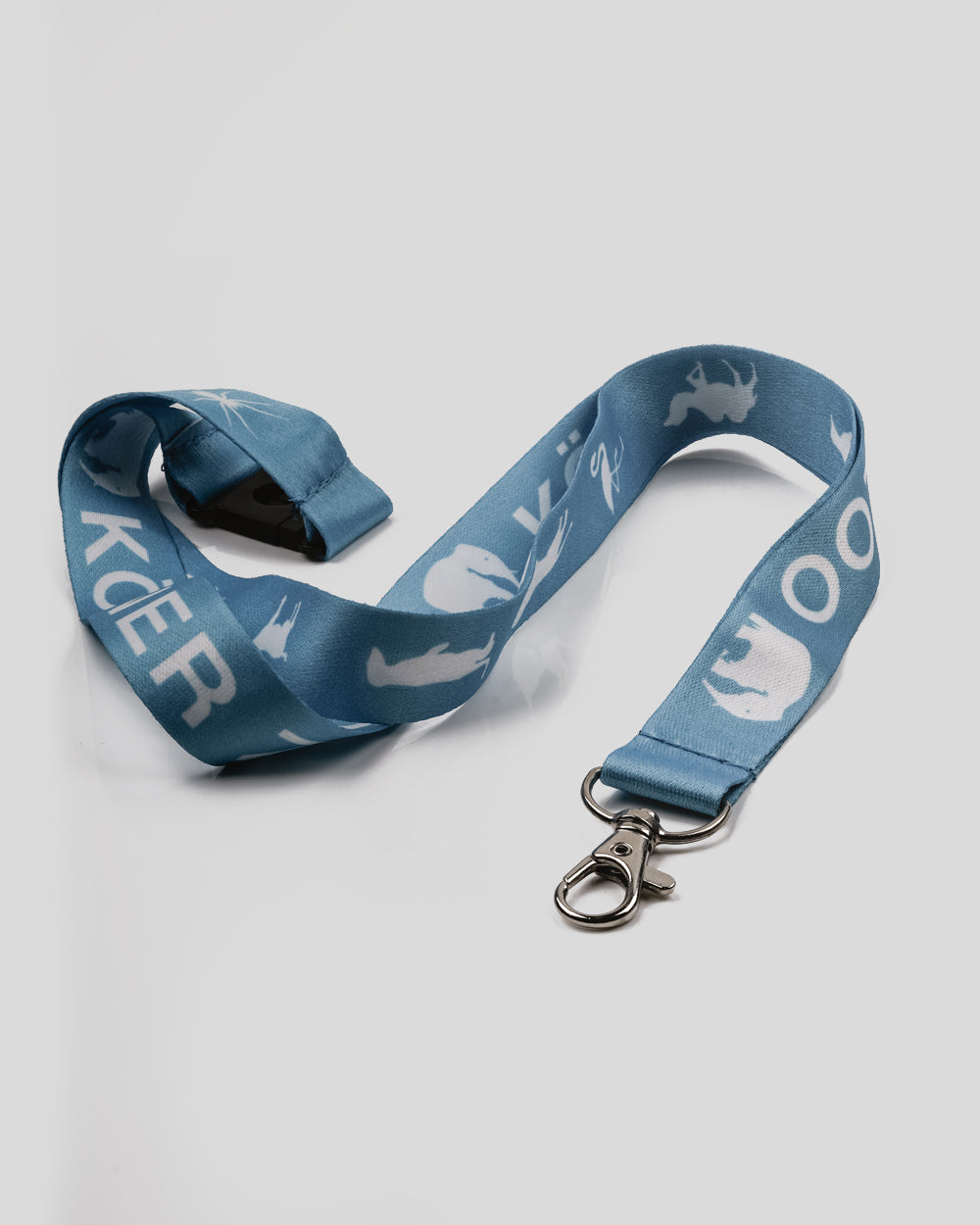Blaues Schlüsselband mit weißem Aufdruck verschiedener Tiersilhouetten und dem Schriftzug ‚Kölner Zoo‘. Das Band hat einen silbernen Metallkarabinerhaken und eine schwarze Sicherheitsverschluss-Schnalle auf der Rückseite.