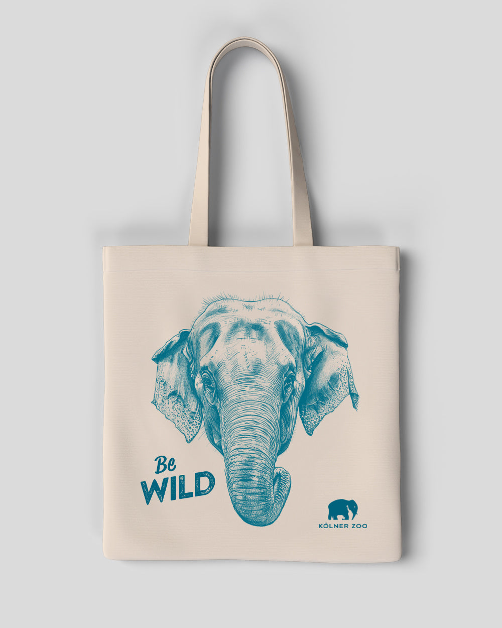 Eine beigefarbene Stofftasche mit zwei Henkeln. Auf der Vorderseite ist ein detailliertes, blaues Porträt eines Elefantenkopfes abgebildet. Links daneben steht der Schriftzug „Be WILD“ in blauer Schrift. Unten rechts ist das Logo des Kölner Zoos mit einem kleinen Elefantenmotiv und dem Text „KÖLNER ZOO“ zu sehen.